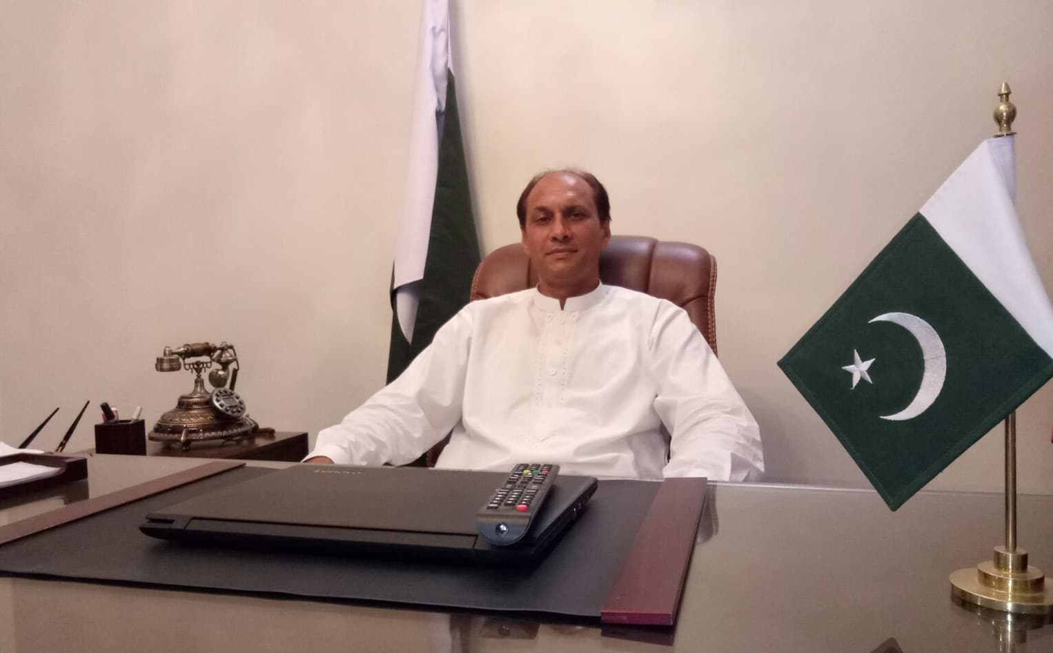 Medium portrait of Sardar Altaf Hussain Anwar seated at office desk